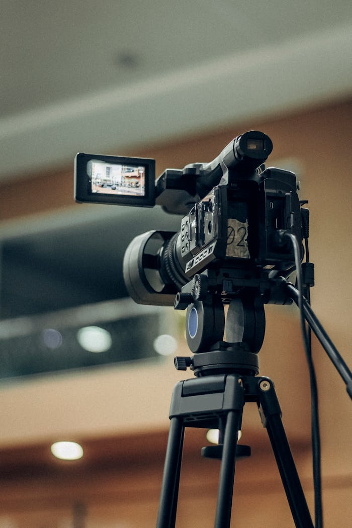 A high-quality video camcorder setup on a tripod for indoor filming.